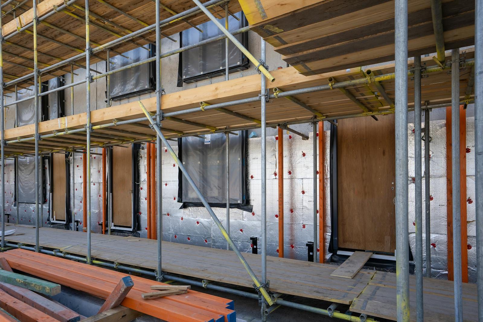 Chantier d'isolation par l'extérieur — panneaux rigides, ancrages à rosaces et échafaudage